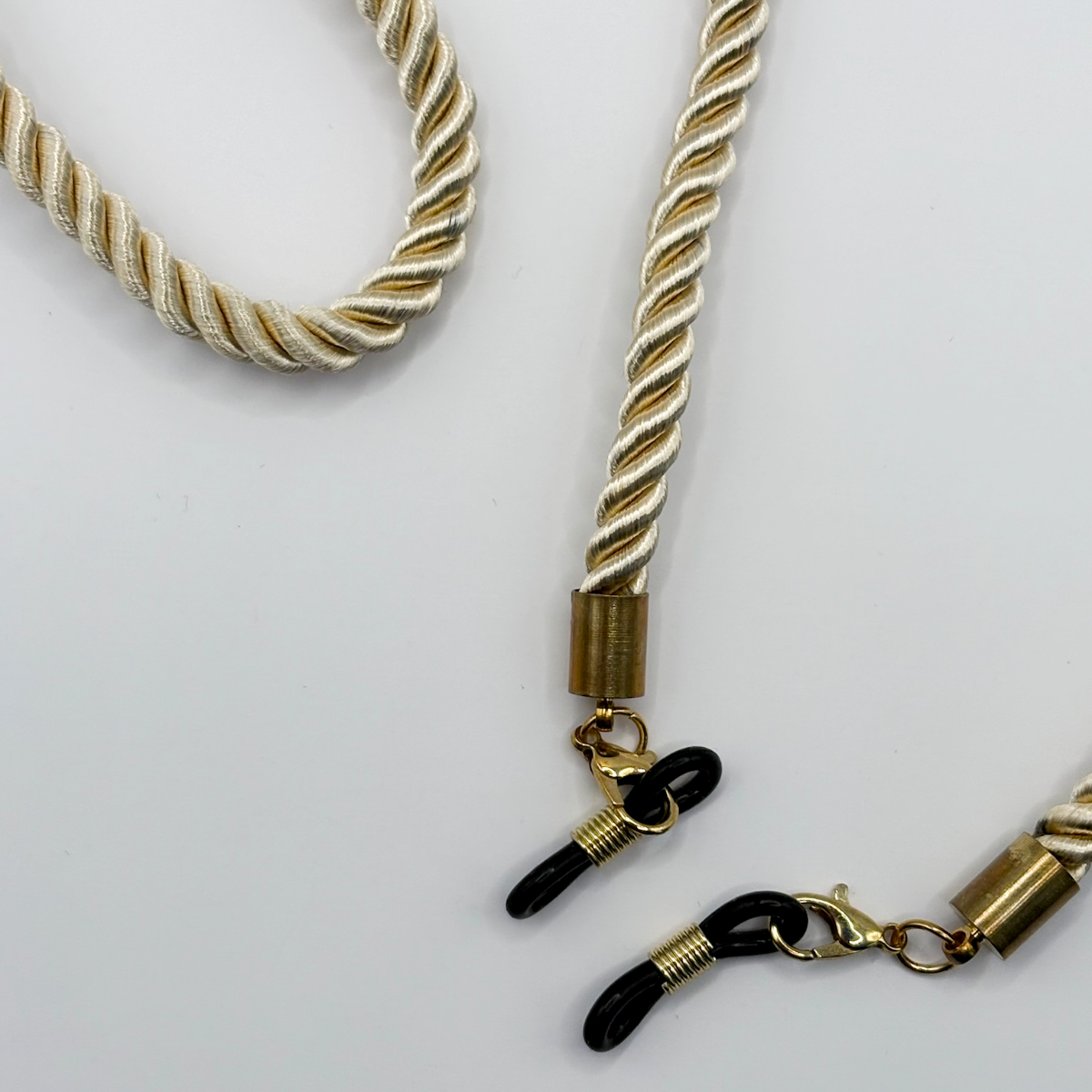 Gold and black necklace with rope-like design on a white background