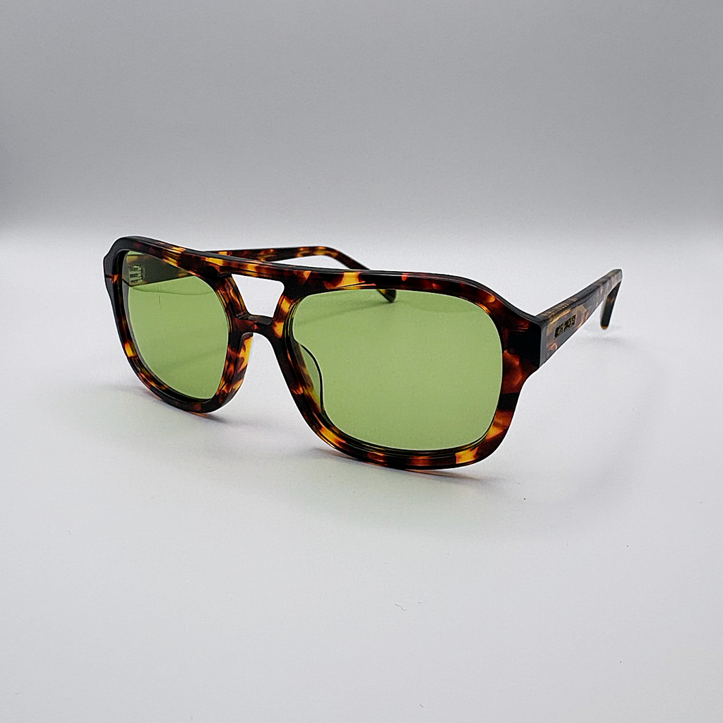 Close-up of vintage-inspired frame crafted from premium brown tortoiseshell acetate and yellow green tinted lensesfrom independent rock ’n’ roll–inspired eyewear brand Dirty Rocker. David Bowie inspired sunglasses.