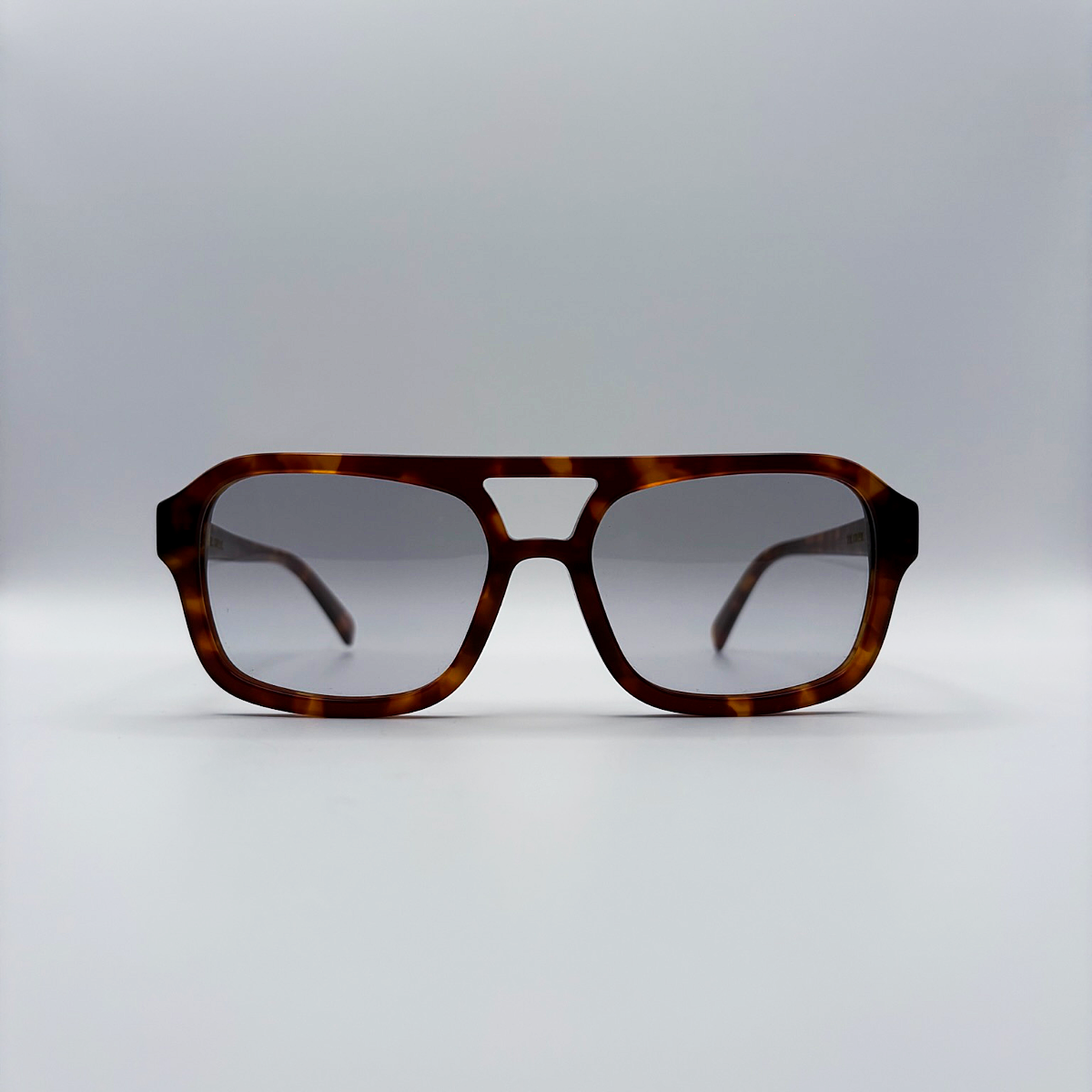 Close-up of vintage-inspired frame crafted from premium brown tortoiseshell acetate and grey-tinted lensesfrom independent rock ’n’ roll–inspired eyewear brand Dirty Rocker. David Bowie inspired sunglasses.
