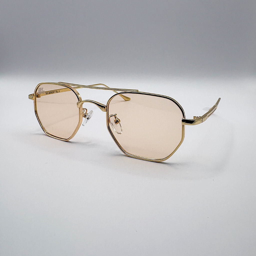 Gold-framed sunglasses with beige lenses on a light gray background