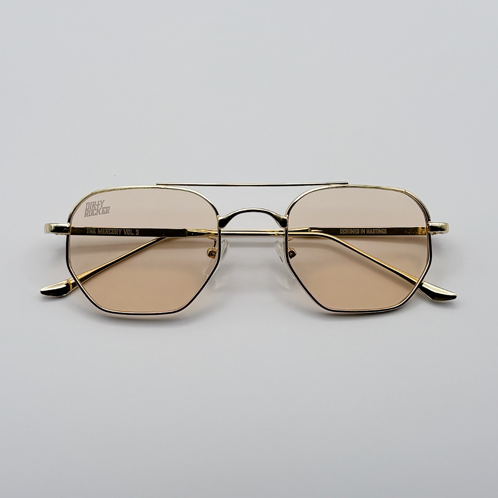 Gold-framed sunglasses with brown lenses on a light gray background