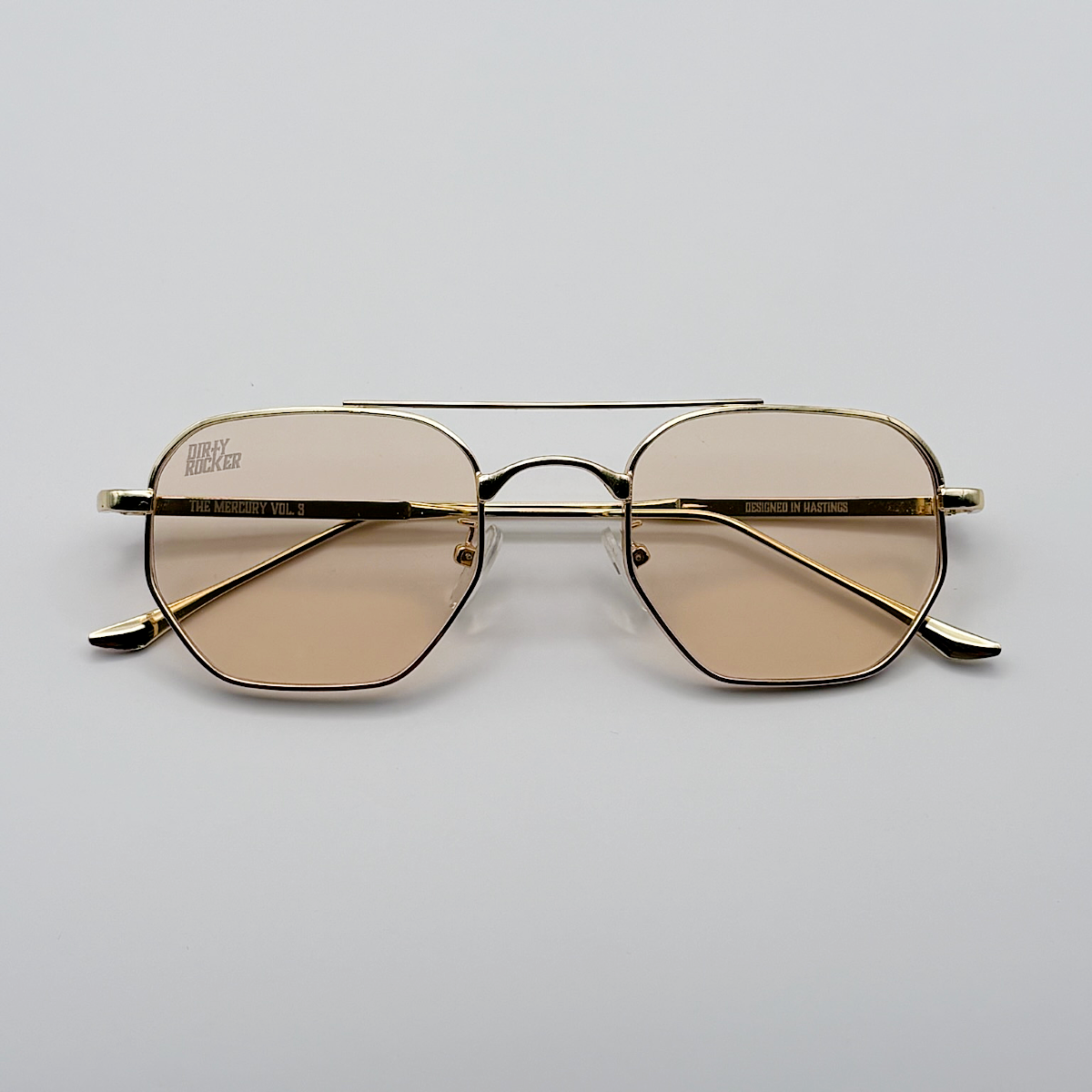 Gold-framed sunglasses with brown lenses on a light gray background